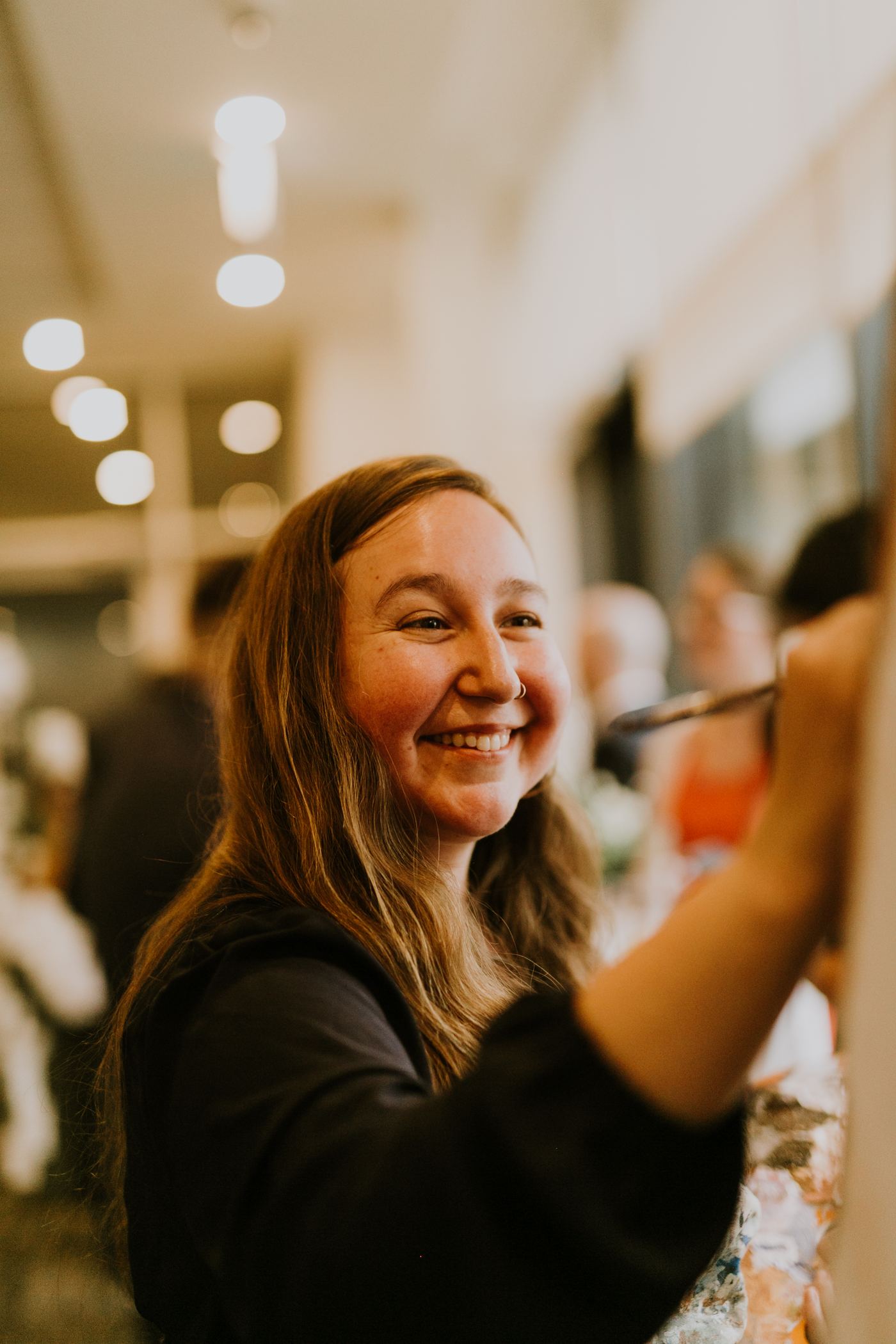 Heather LeBlanc painting live at a wedding reception, smiling as she works