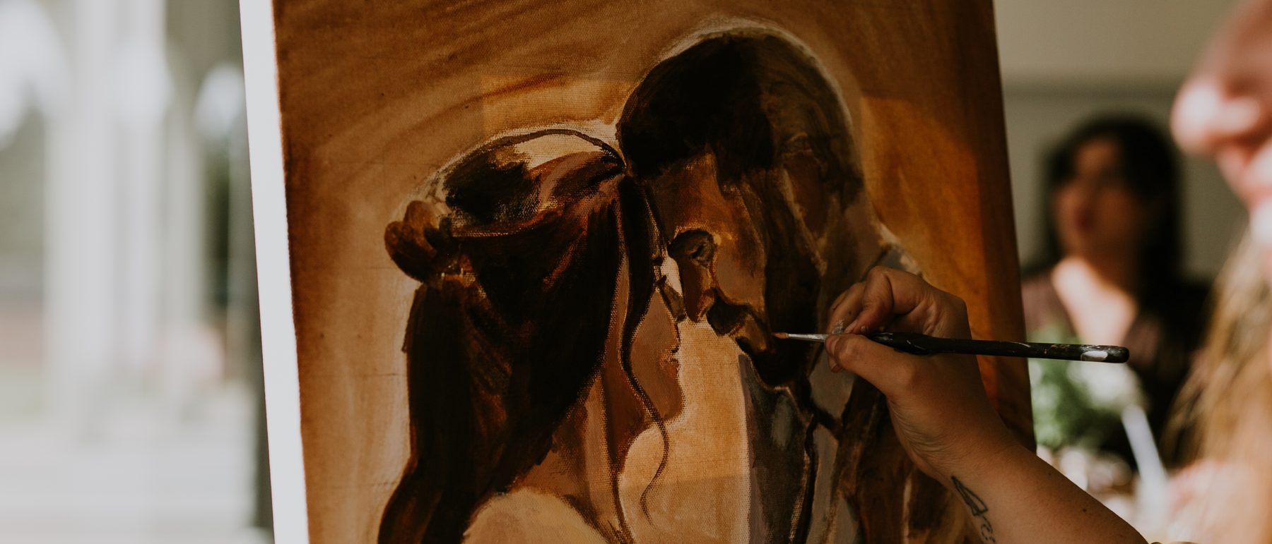Heather LeBlanc painting a couple's portrait live, brush and hand on the canvas
