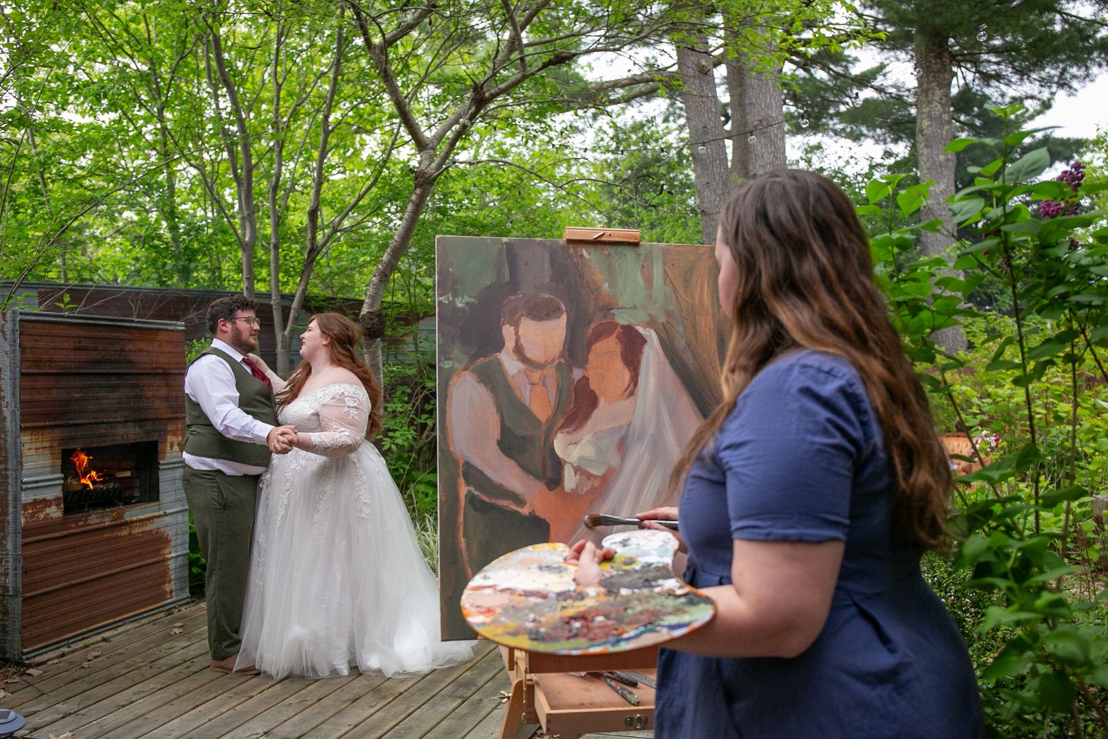 A newly married couple dancing outdoors as Heather paints their portrait live at an easel nearby