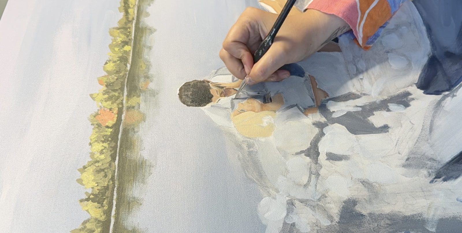 A close view of the brush working pale blue and white paint into the flowers on the boat