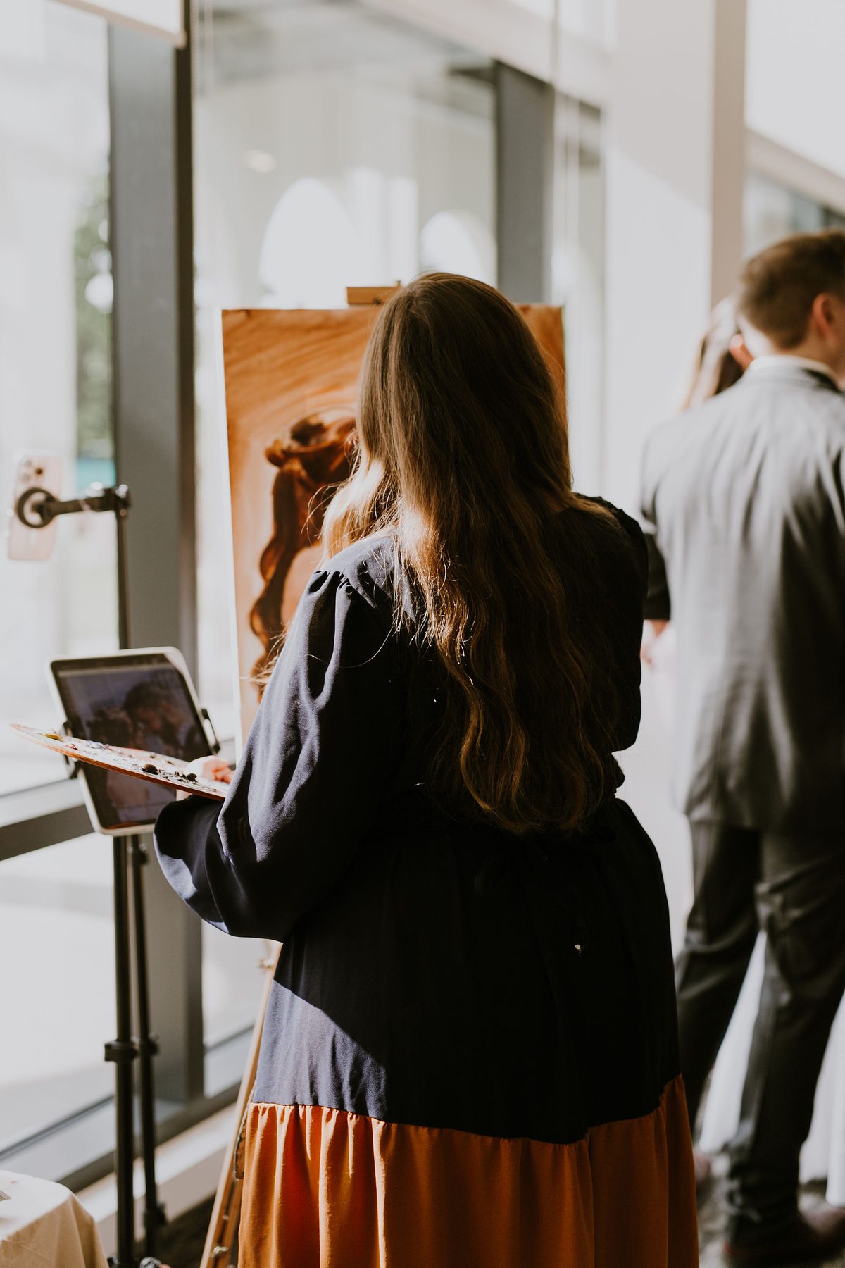 Heather working from her sketch and a reference photograph on an easel-mounted tablet